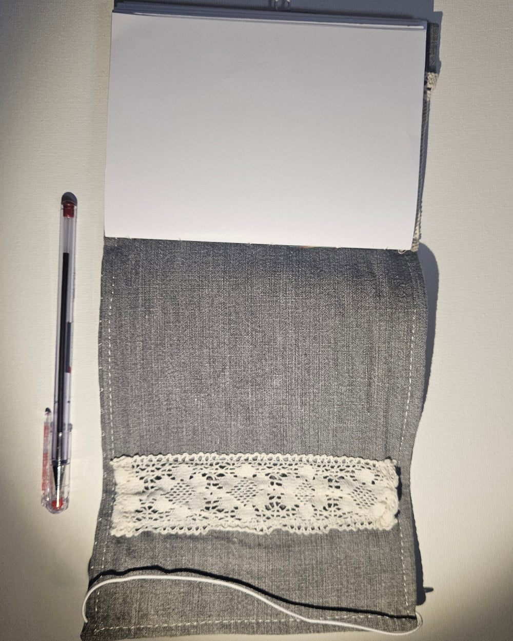 grey notbook open on back with a pen
